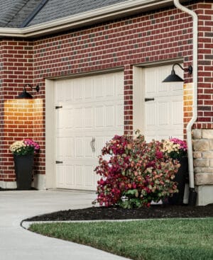 A brick home with two garage doors and a flower pot.